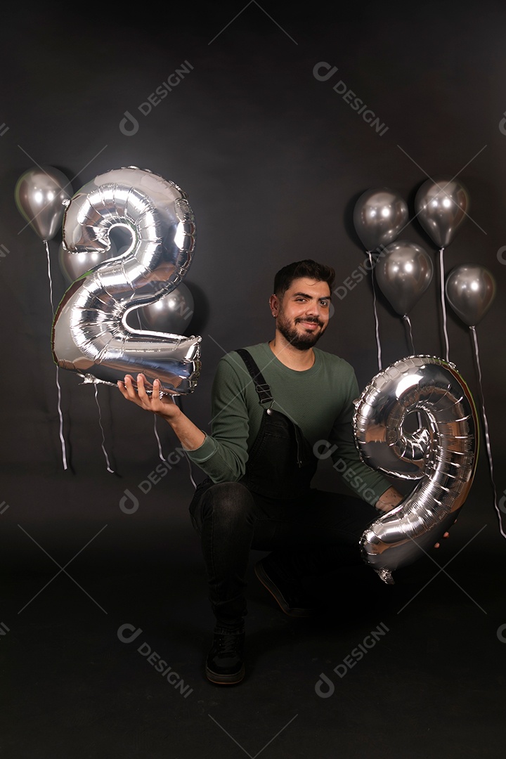 Lindo homem sorridente fazendo aniversário sobre fundo com balões isolado