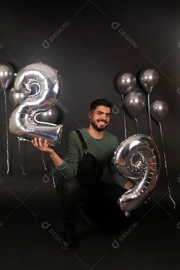 Lindo homem sorridente fazendo aniversário sobre fundo com balões isolado