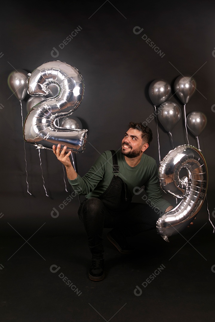 Lindo homem sorridente fazendo aniversário sobre fundo com balões isolado