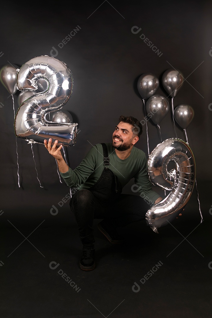 Lindo homem sorridente fazendo aniversário sobre fundo com balões isolado