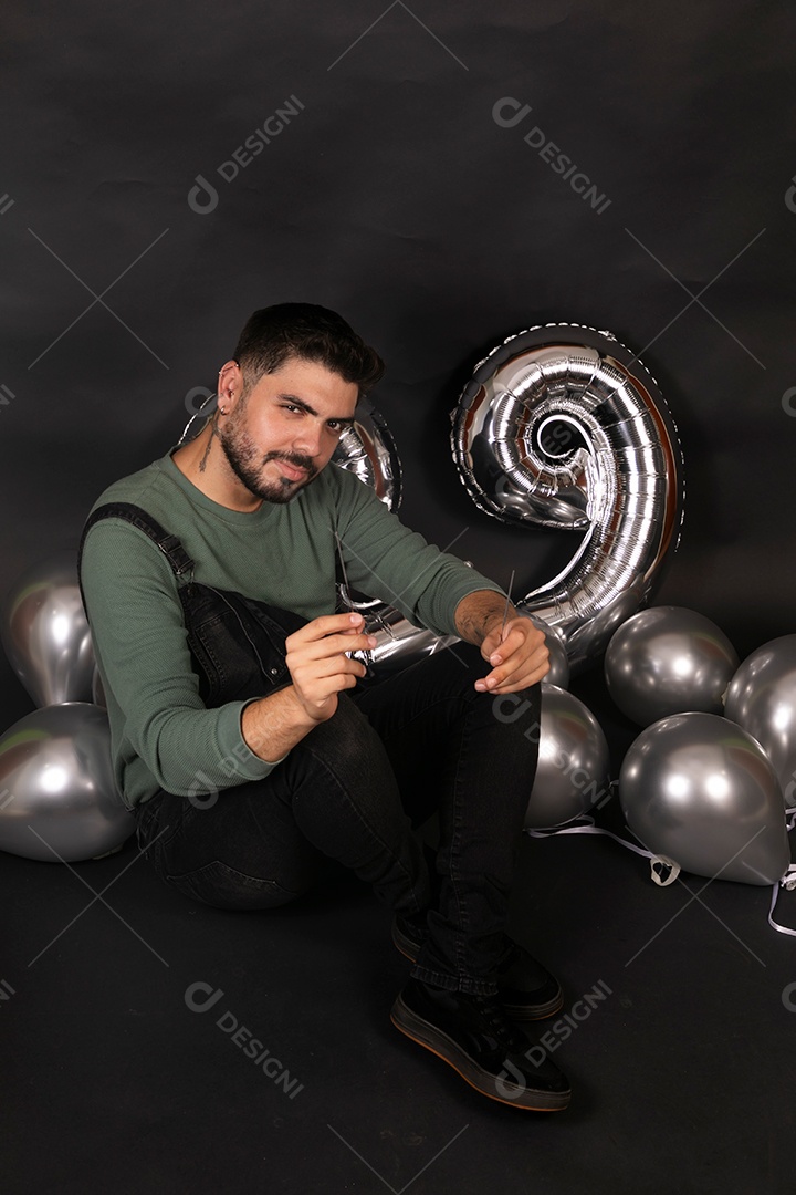 Lindo homem sorridente fazendo aniversário sobre fundo com balões isolado