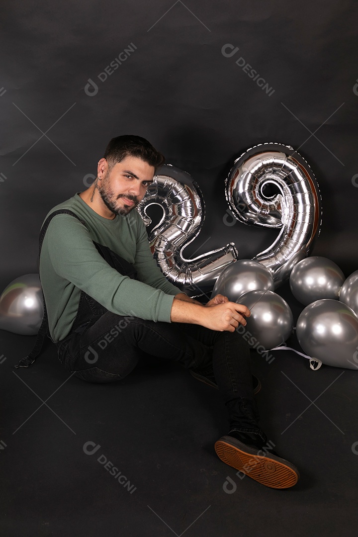 Lindo homem sorridente fazendo aniversário sobre fundo com balões isolado