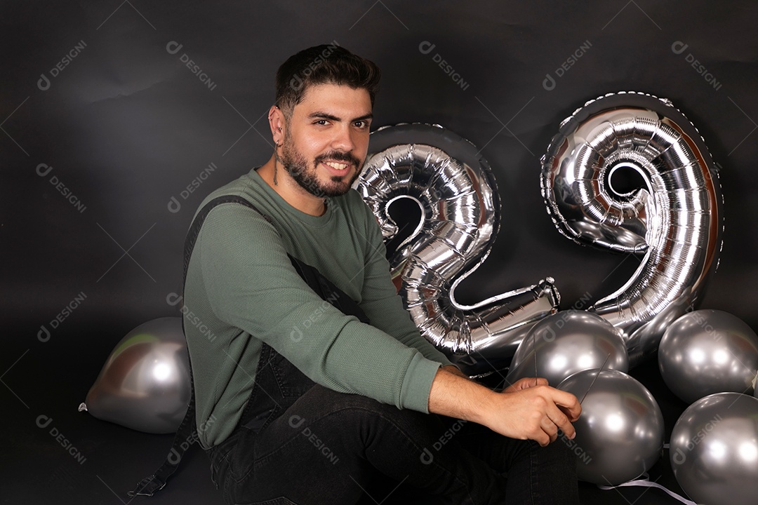Lindo homem sorridente fazendo aniversário sobre fundo com balões isolado