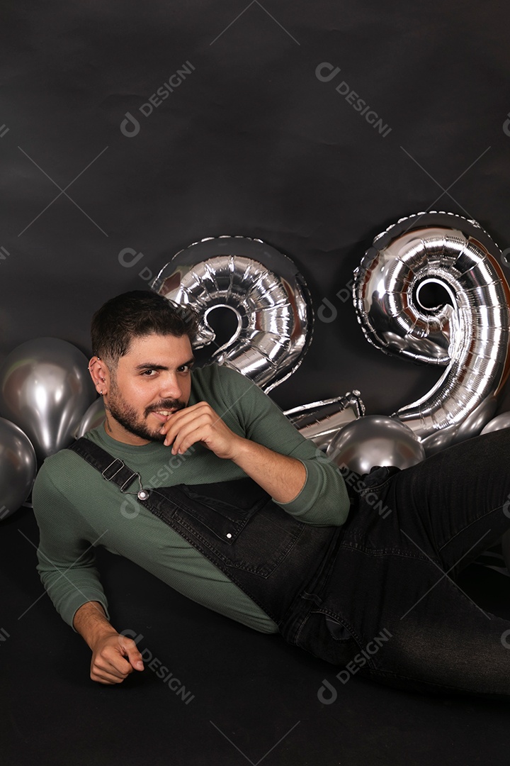 Lindo homem sorridente fazendo aniversário sobre fundo com balões isolado