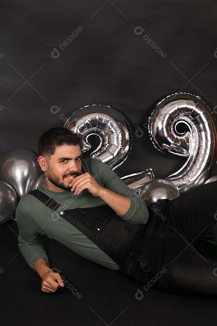 Lindo homem sorridente fazendo aniversário sobre fundo com balões isolado