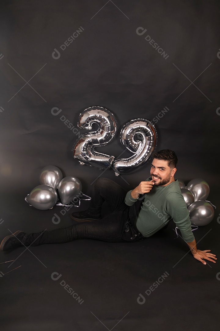Lindo homem sorridente fazendo aniversário sobre fundo com balões isolado