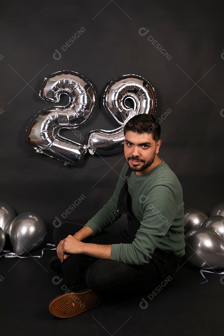 Lindo homem sorridente fazendo aniversário sobre fundo com balões isolado