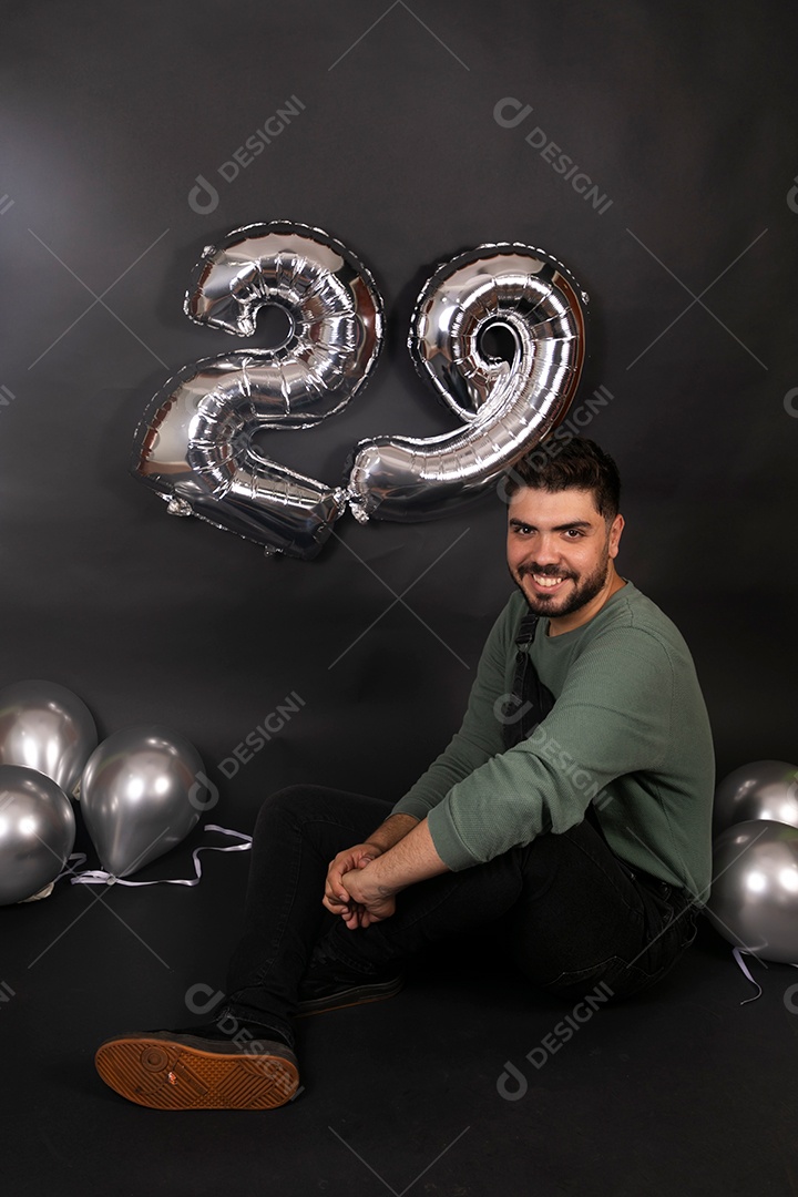 Linda homem sorridente com macacão preto segurando balões sobre fundo isolado