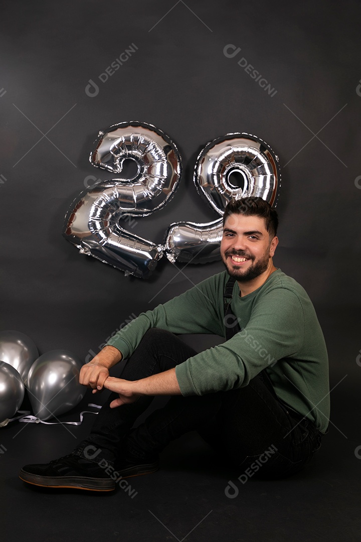 Linda homem sorridente com macacão preto segurando balões sobre fundo isolado