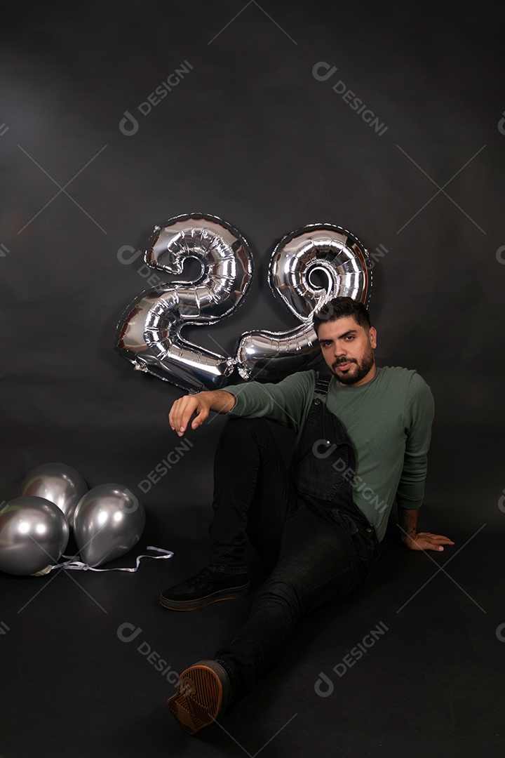 Linda homem com macacão preto segurando balões sobre fundo isolado