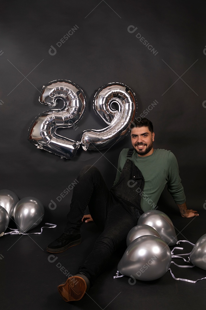 Linda homem sorridente com macacão preto segurando balões sobre fundo isolado
