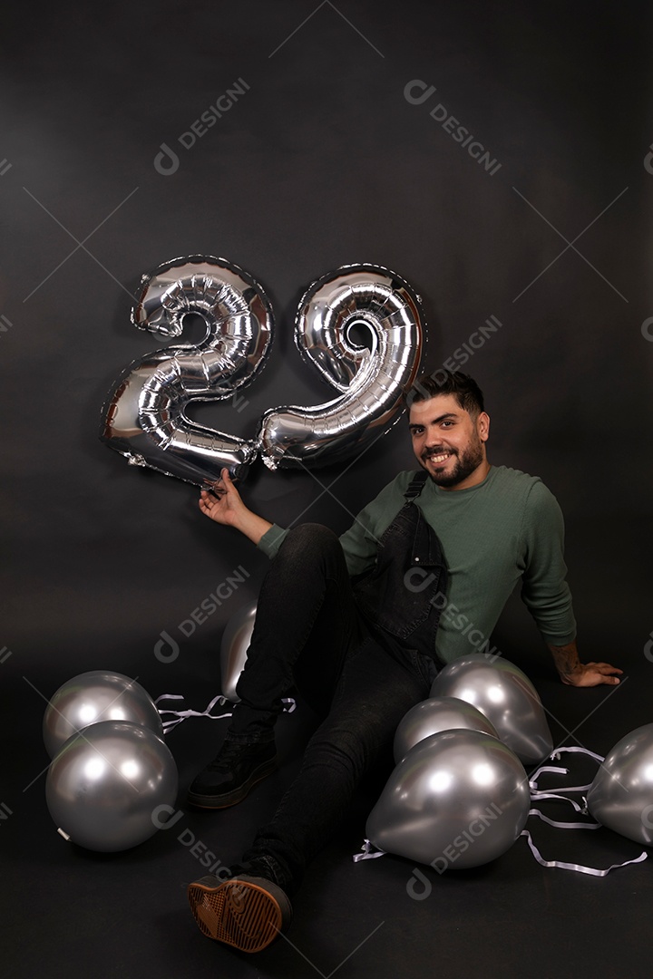 Linda homem sorridente com macacão preto segurando balões sobre fundo isolado