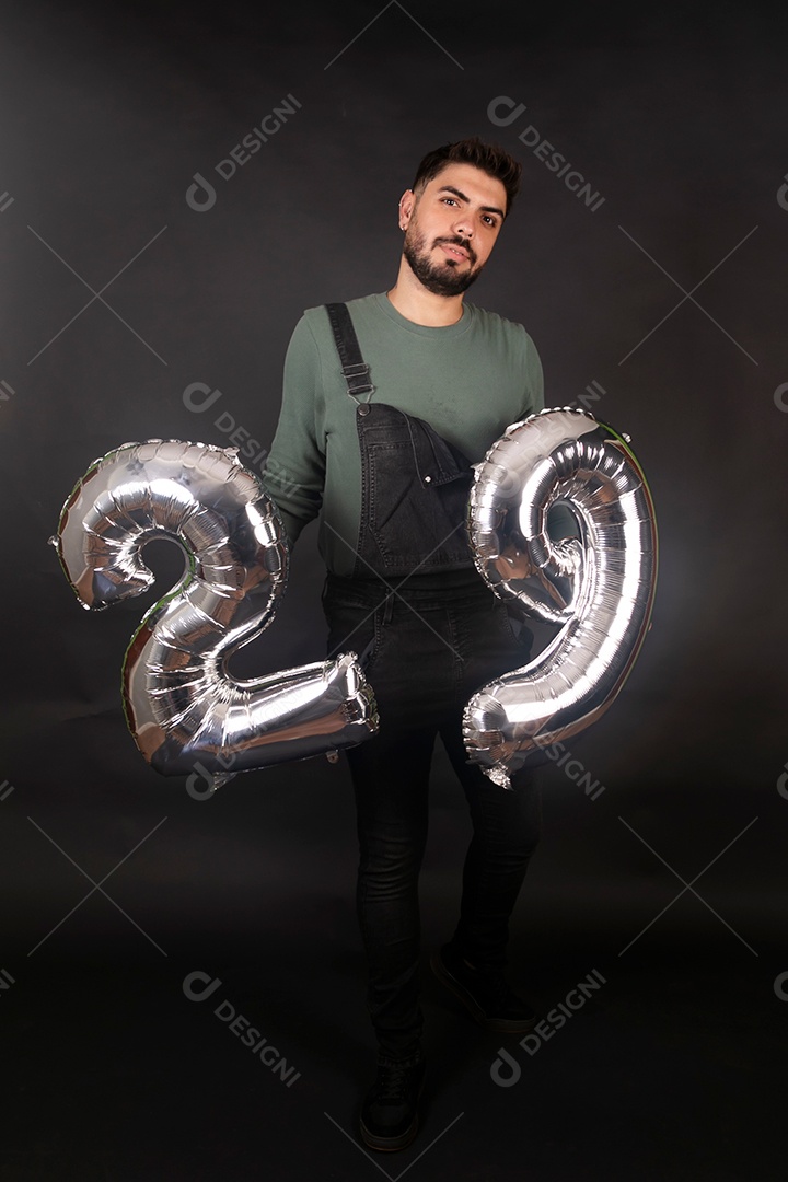 Linda homem com macacão preto segurando balões sobre fundo isolado