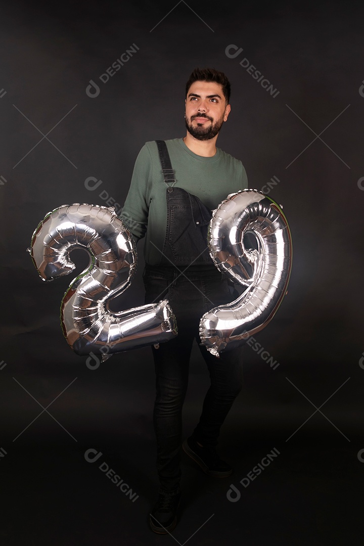 Linda homem com macacão preto segurando balões sobre fundo isolado