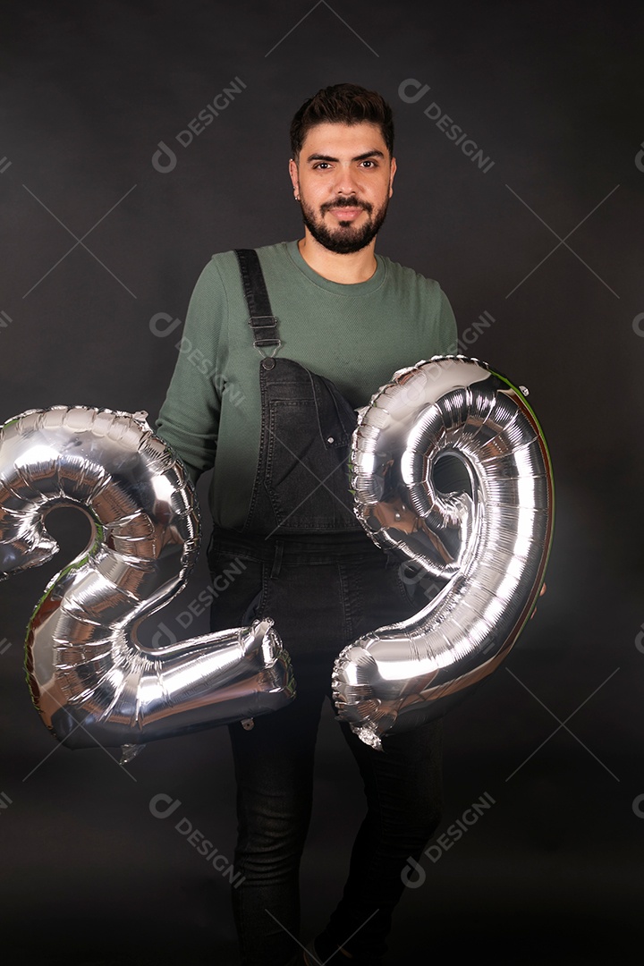 Linda homem com macacão preto segurando balões sobre fundo isolado