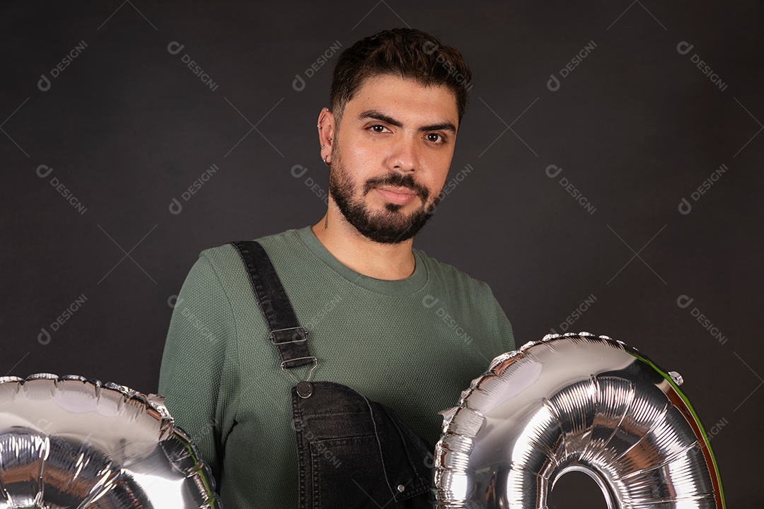 Linda homem com macacão preto segurando balões sobre fundo isolado