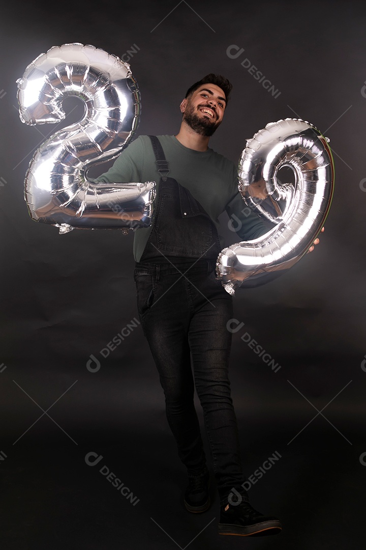 Linda homem sorridente com macacão preto segurando balões sobre fundo isolado