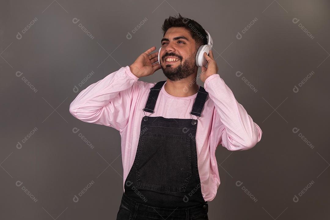 Lindo homem com macacão preto usando fone de ouvido sobre fundo isolado