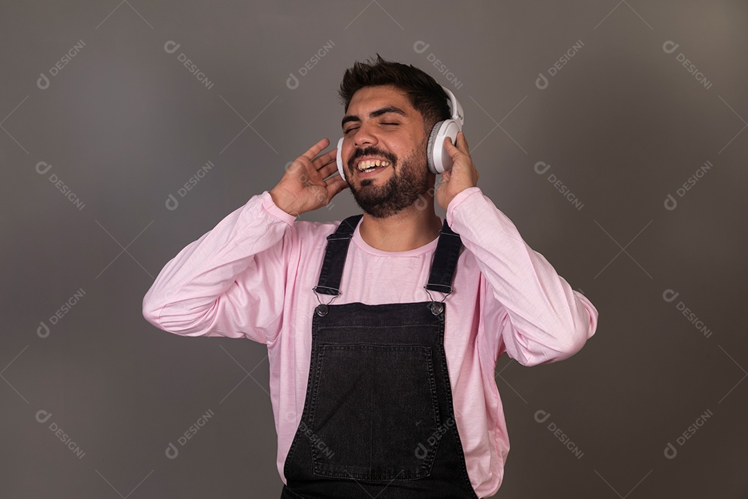 Lindo homem com macacão preto usando fone de ouvido sobre fundo isolado