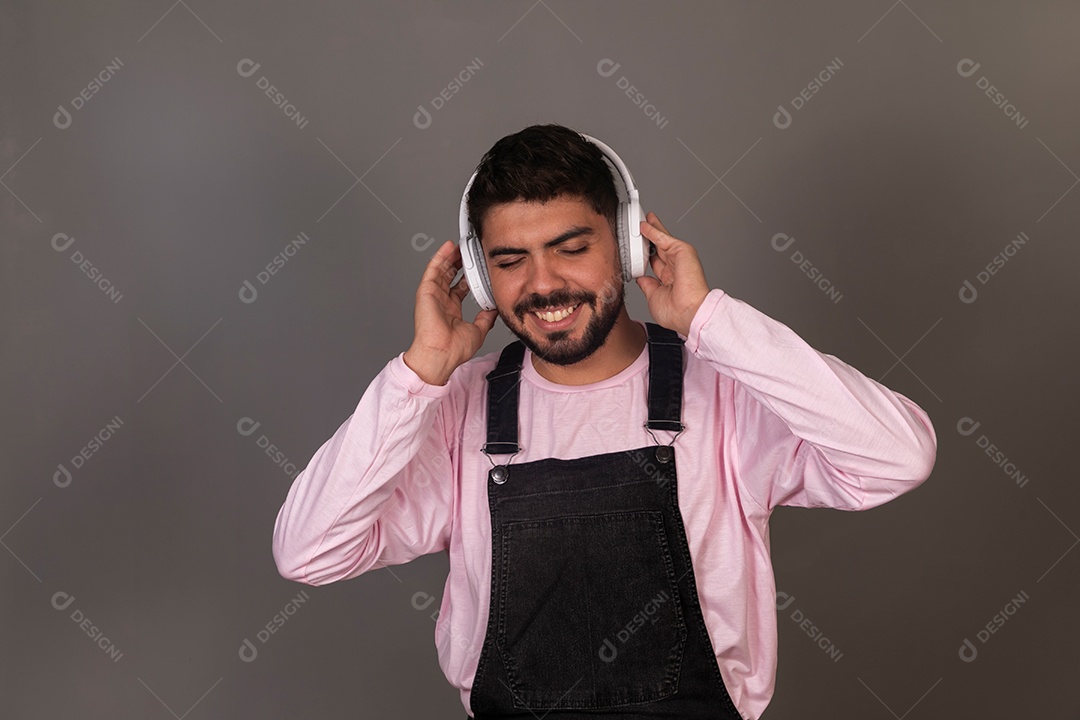Lindo homem com macacão preto usando fone de ouvido sobre fundo isolado