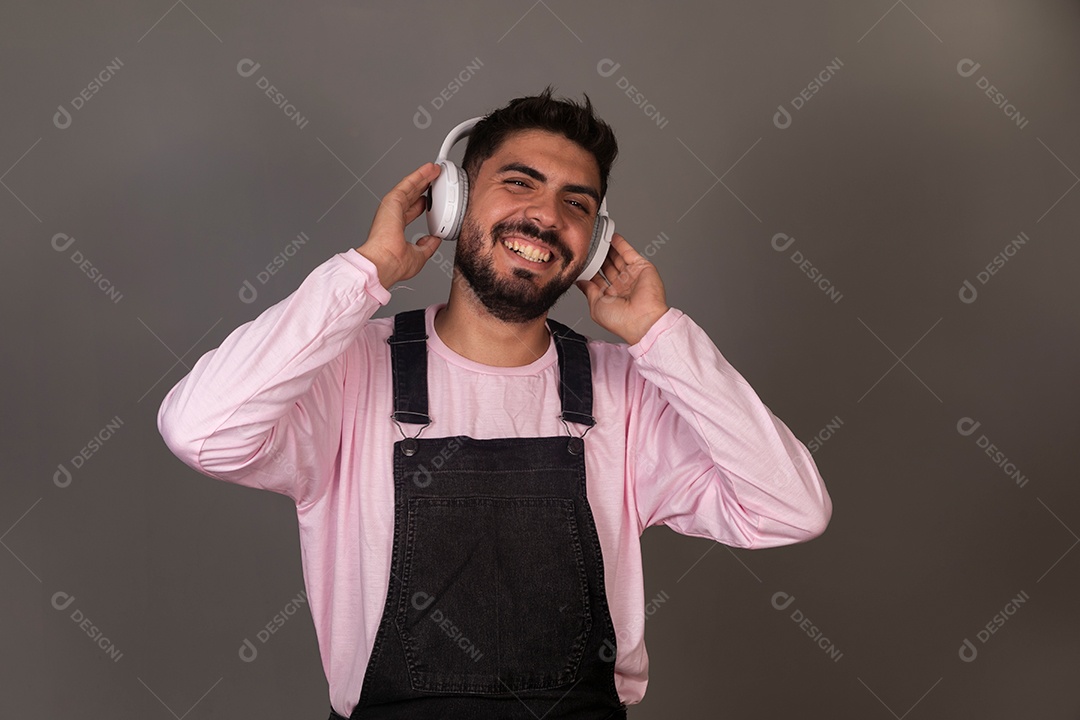 Lindo homem com macacão preto usando fone de ouvido sobre fundo isolado