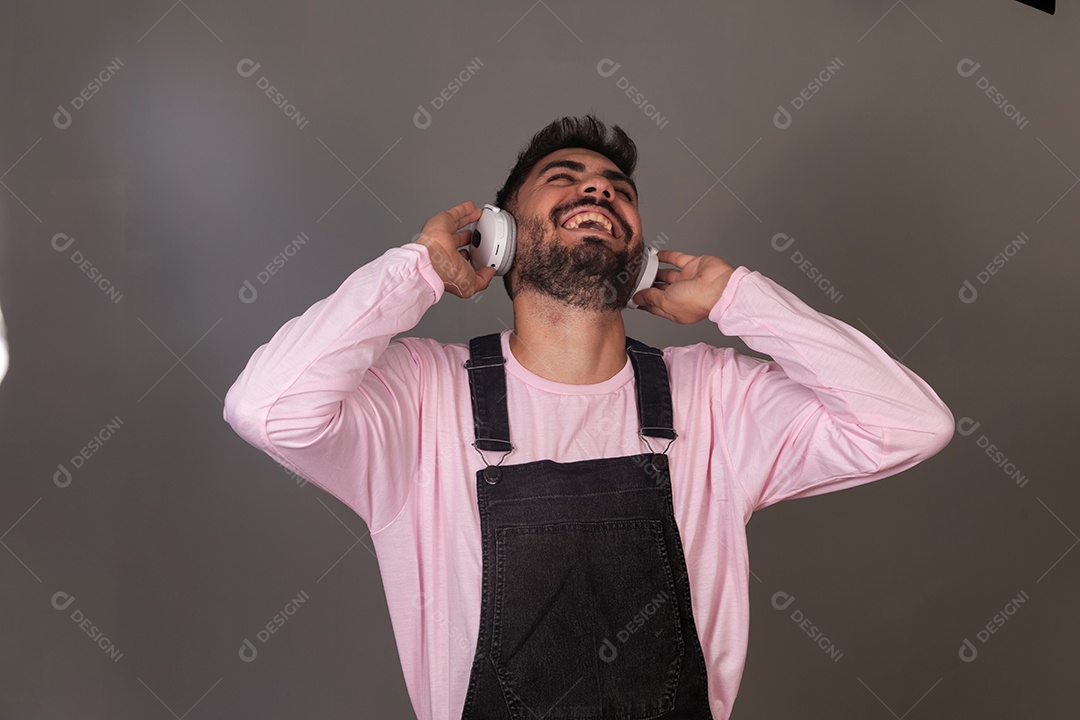 Lindo homem com macacão preto usando fone de ouvido sobre fundo isolado