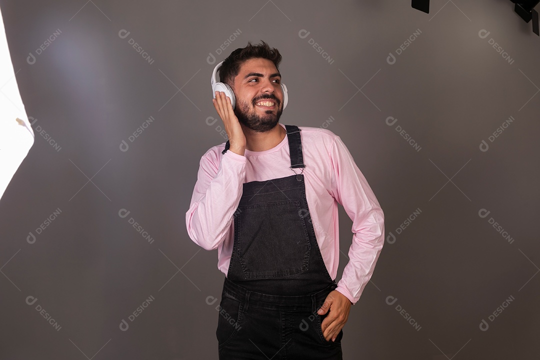 Lindo homem com macacão preto usando fone de ouvido sobre fundo isolado