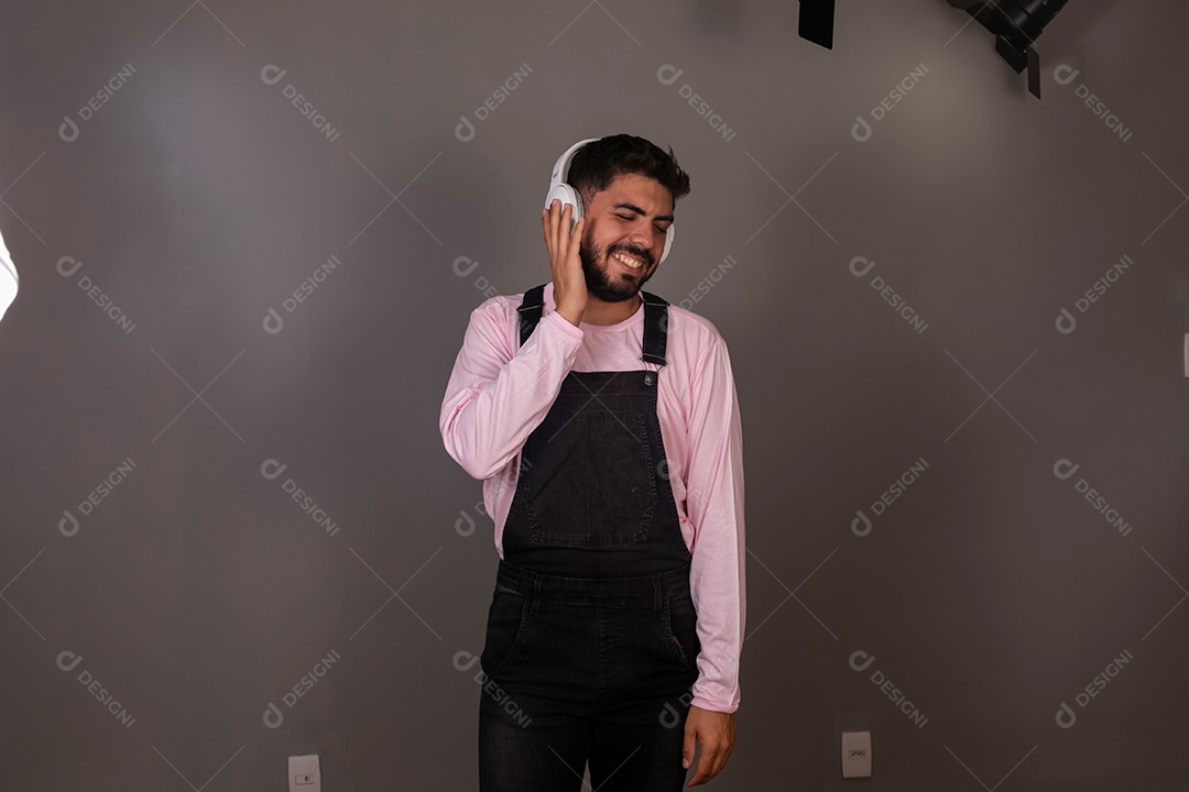 Lindo homem com macacão preto usando fone de ouvido sobre fundo isolado