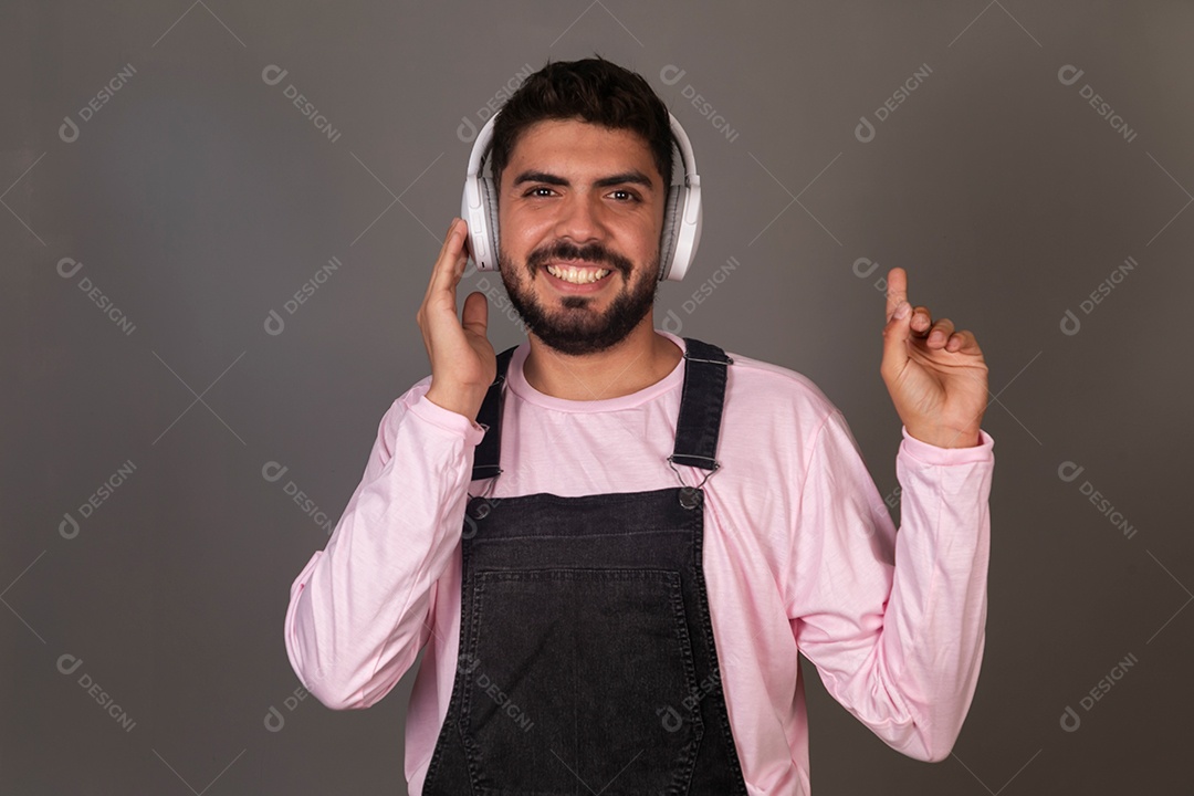 Lindo homem com macacão preto usando fone de ouvido sobre fundo isolado