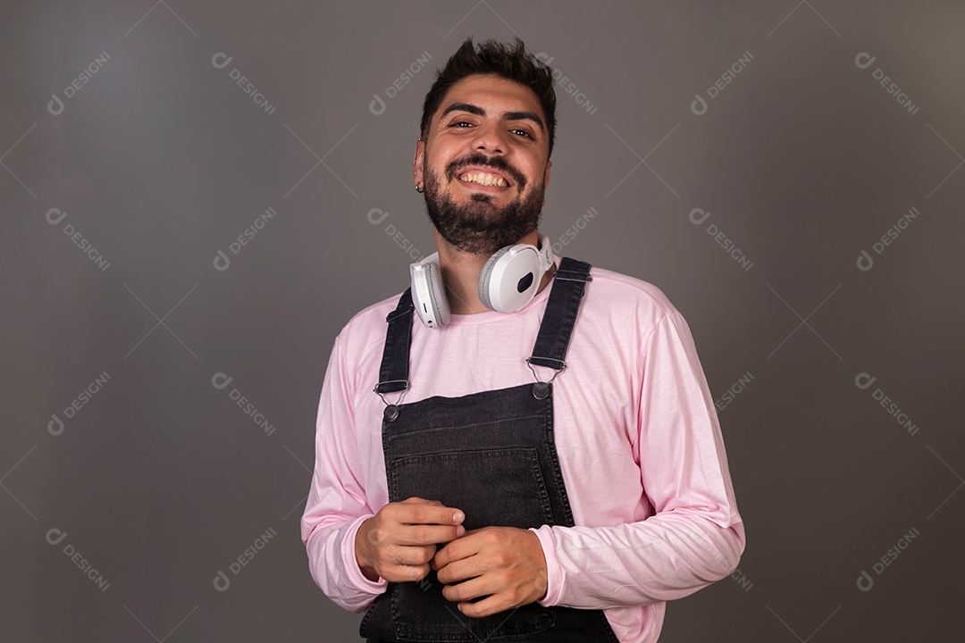 Lindo homem com macacão preto usando fone de ouvido sobre fundo isolado