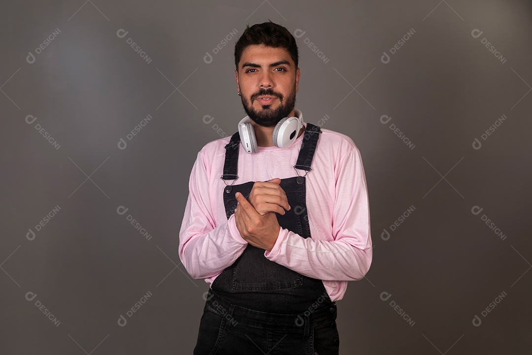 Lindo homem com macacão preto usando fone de ouvido sobre fundo isolado