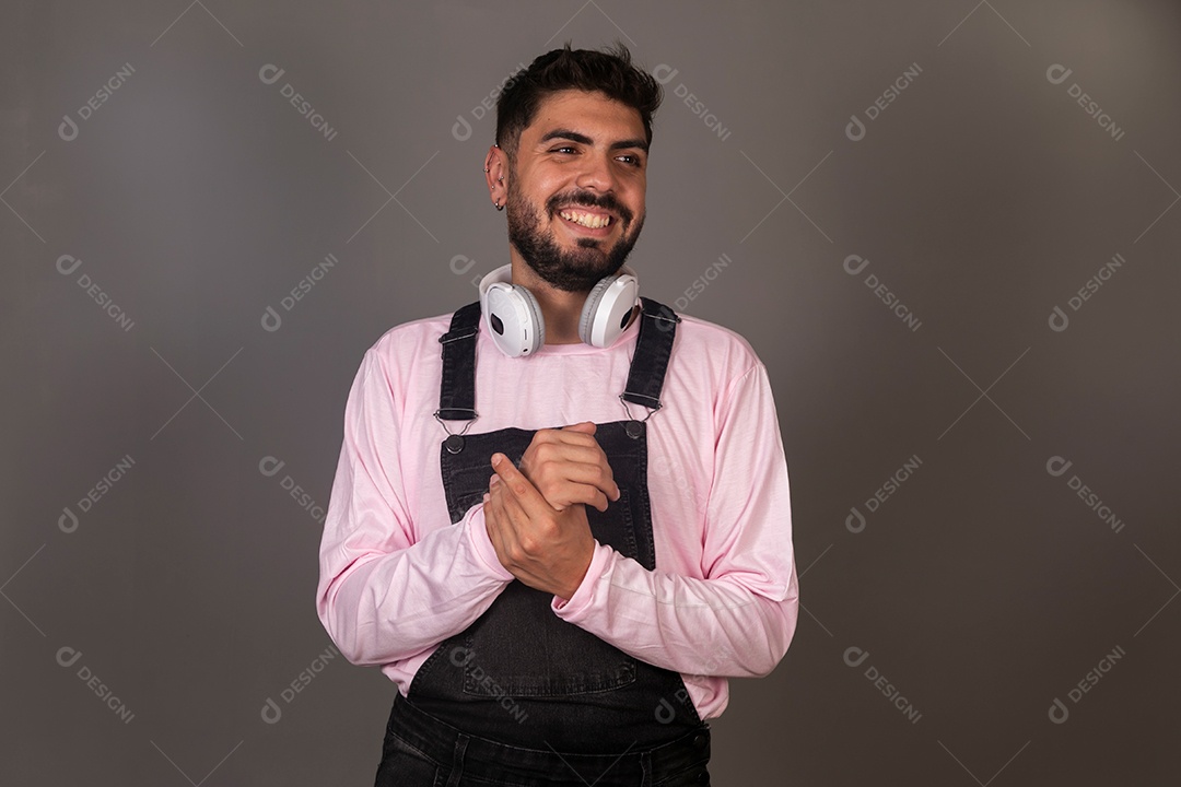 Lindo homem com macacão preto usando fone de ouvido sobre fundo isolado