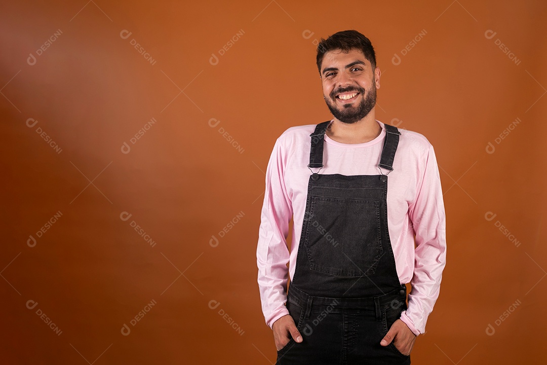 Lindo homem usando macacão preto sobre fundo laranja isolado