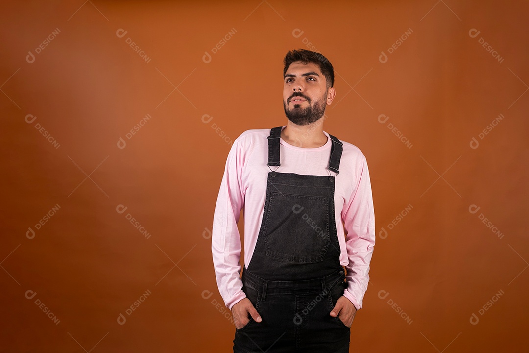 Lindo homem usando macacão preto sobre fundo laranja isolado