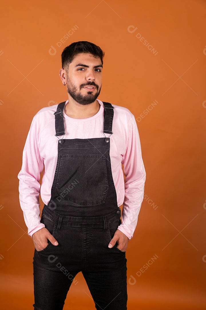 Lindo homem usando macacão preto sobre fundo laranja isolado