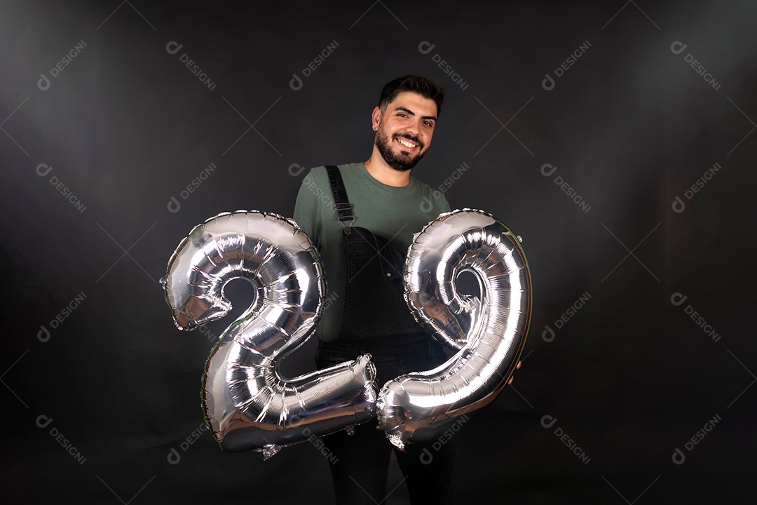 Lindo homem sorridente segurando seus balões de aniversário sobre fundo isolado