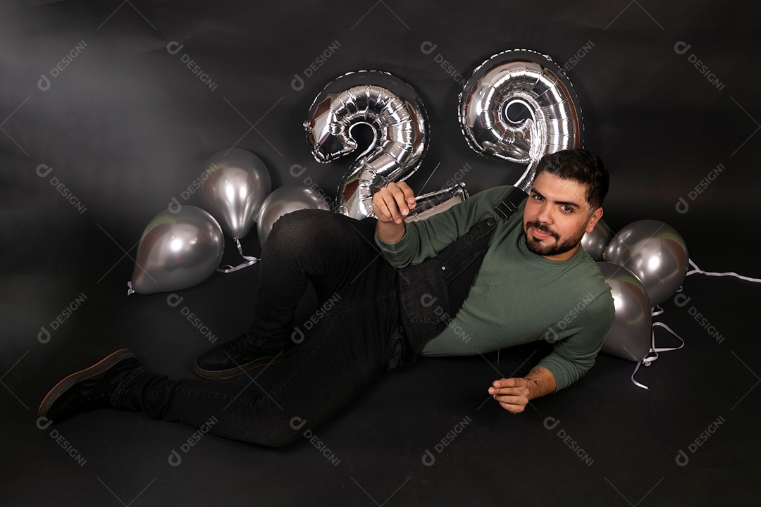 Lindo homem sentado fazendo aniversário sobre fundo com balões isolado