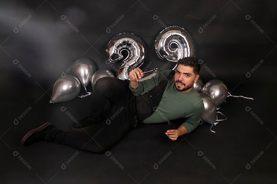 Lindo homem sentado fazendo aniversário sobre fundo com balões isolado