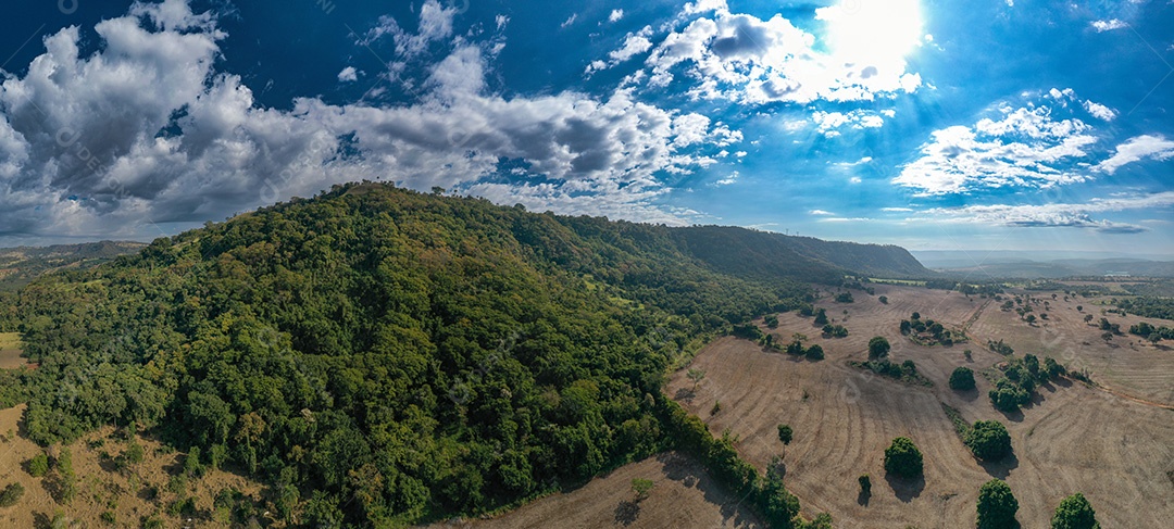 Montanha arborizada com encosta de terra arável