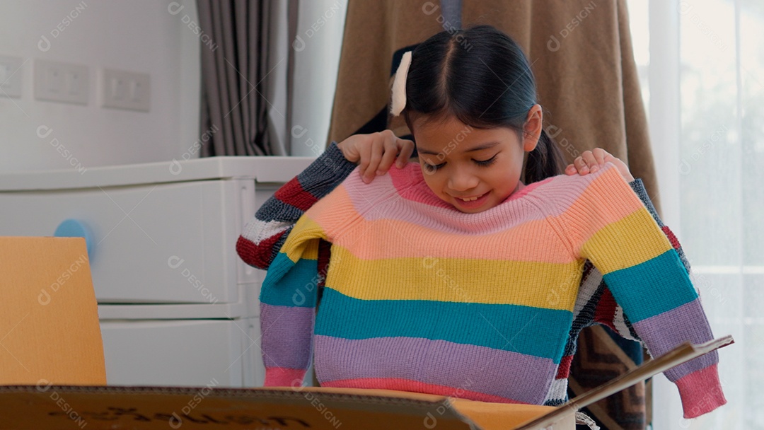 Linda garotinha usando roupa de tricor colorida sobre fundo de um quarto isolado