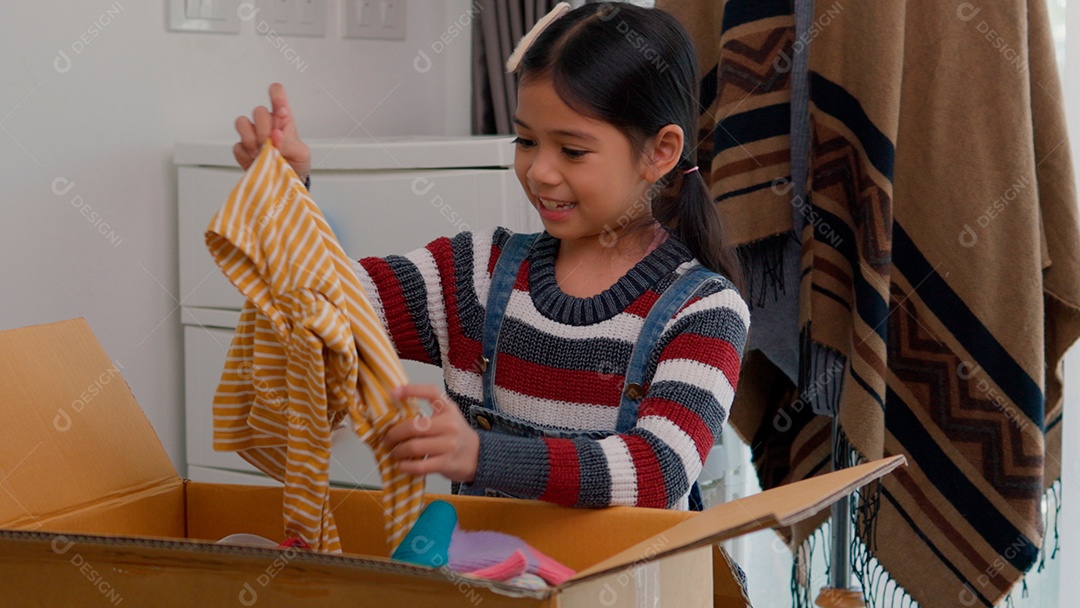 Linda garotinha usando roupa de tricor colorida segurando suéter sobre fundo de um quarto isolado