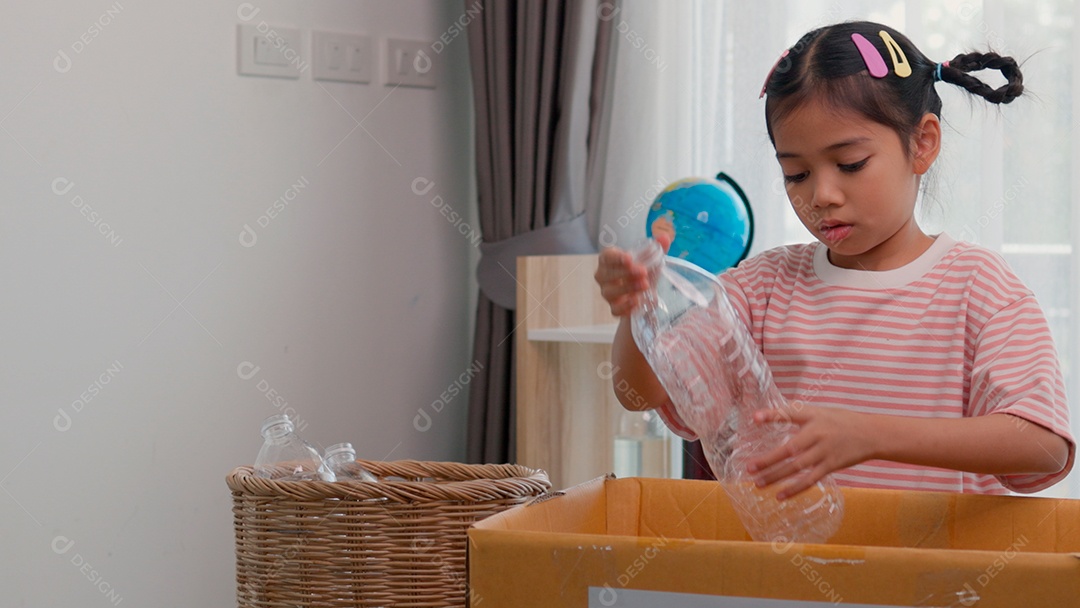 Linda garotinha usando roupa de dormir segurando garrafas de plástico sobre fundo de um quarto isolado