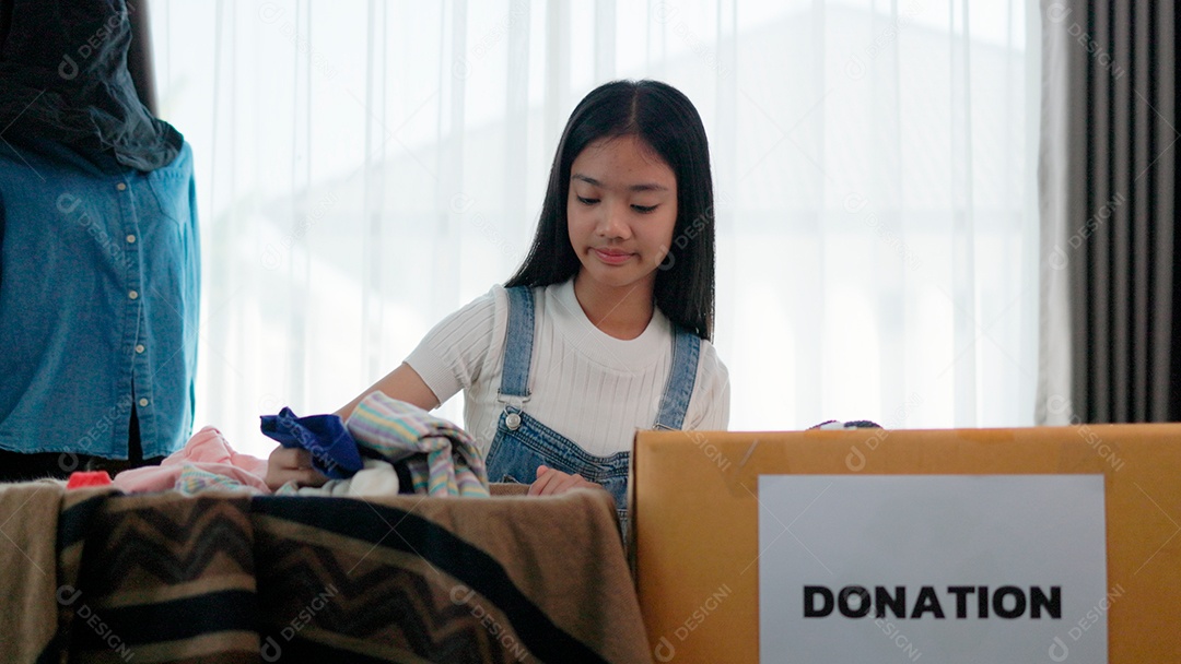 Linda garota sorridente segurando roupas para doação