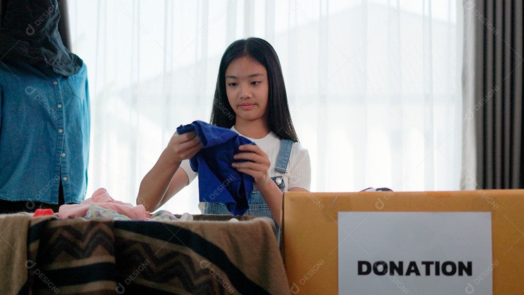 Linda garota sorridente segurando roupas para doação