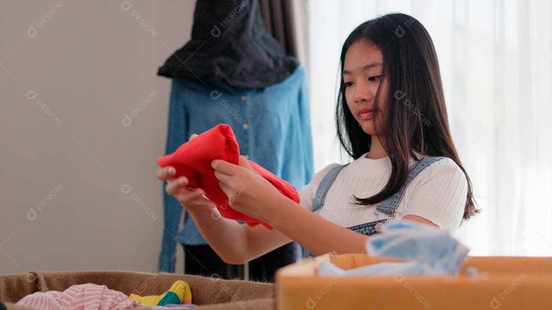 Linda garota sorridente segurando roupas para doação