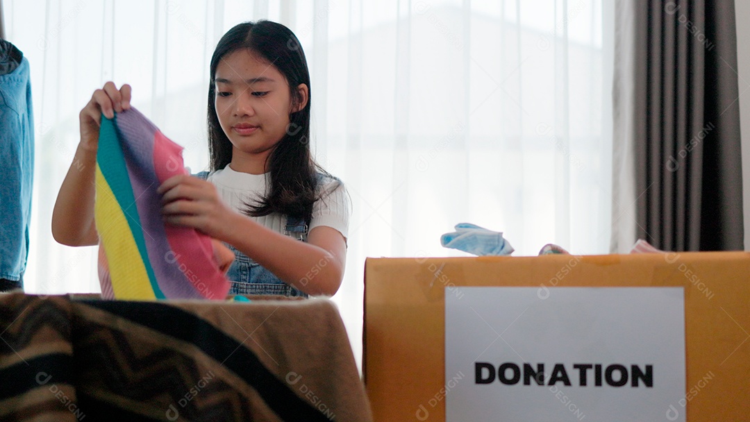 Linda garota sorridente segurando roupas para doação