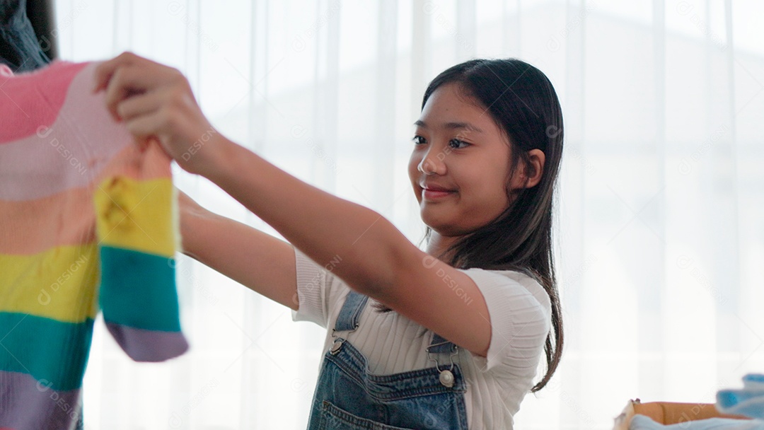 Linda garota sorridente segurando roupas para doação