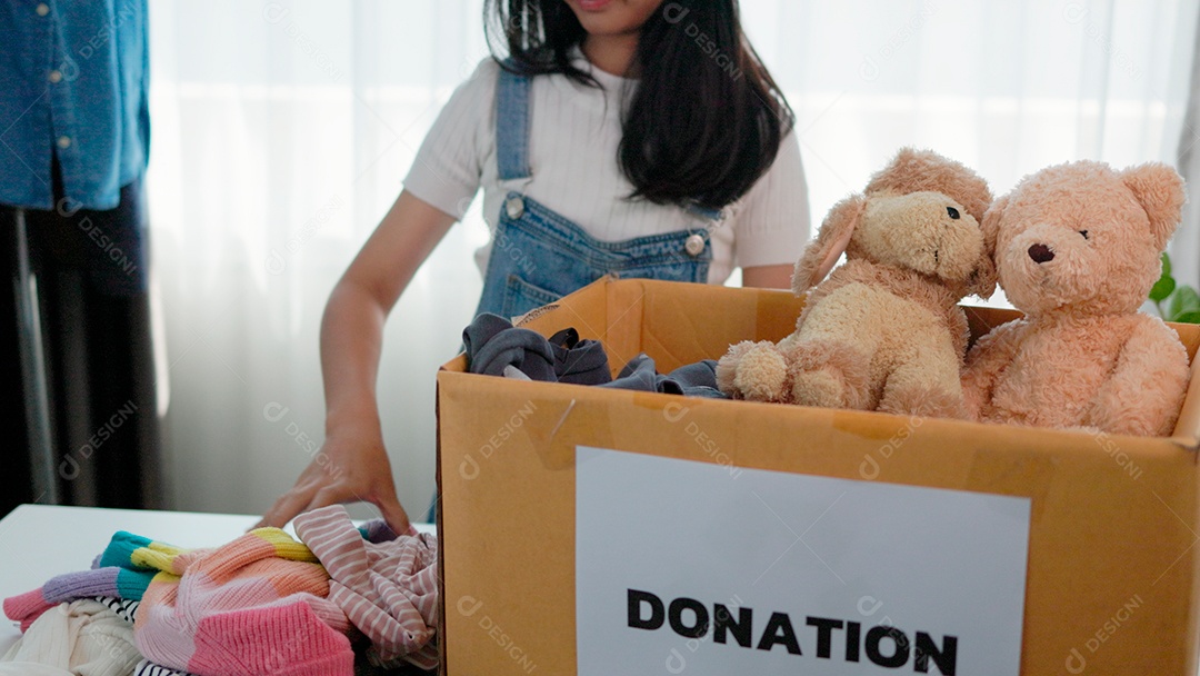 Linda garota sorridente segurando roupas e brinquedos para doação