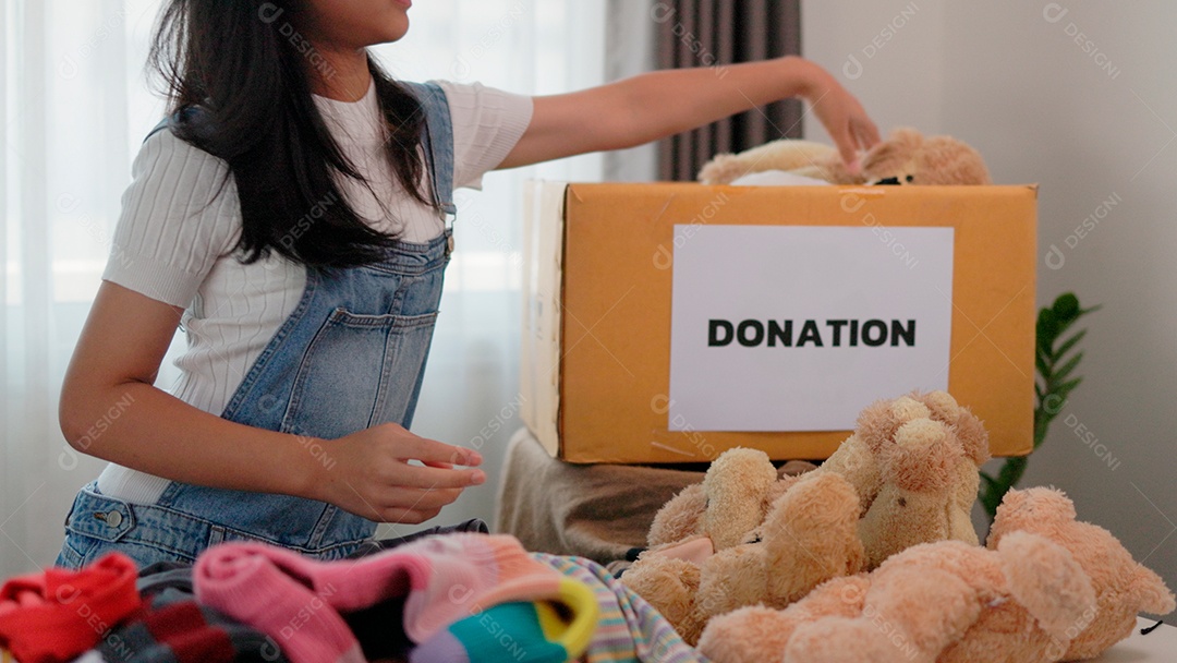 Linda garota sorridente segurando roupas e brinquedos para doação