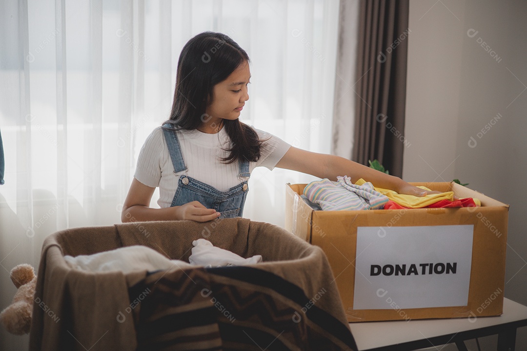 Linda garota sorridente segurando roupas e brinquedos para doação